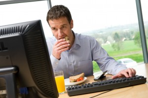 Male office worker eating lunch at computer