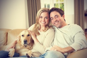 happy-couple-in-their-living-room-with-their-dog