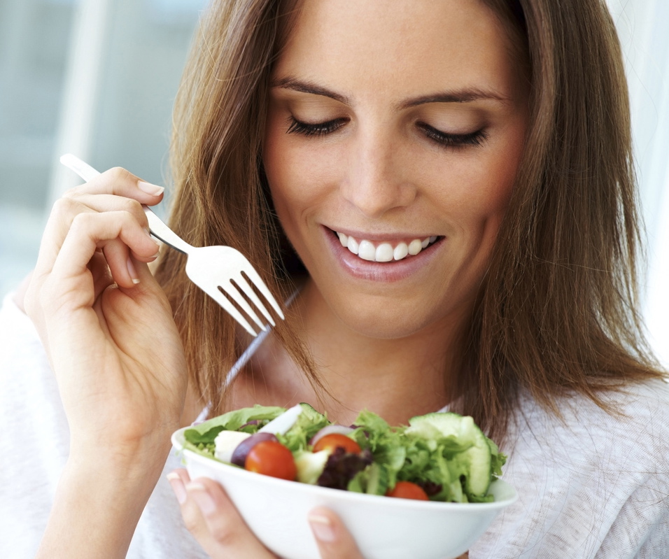 Close-up of young happy woman eating salad